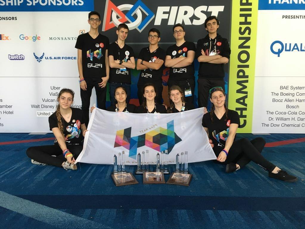 Team members standing with a FIRST Championship sponsor display.
